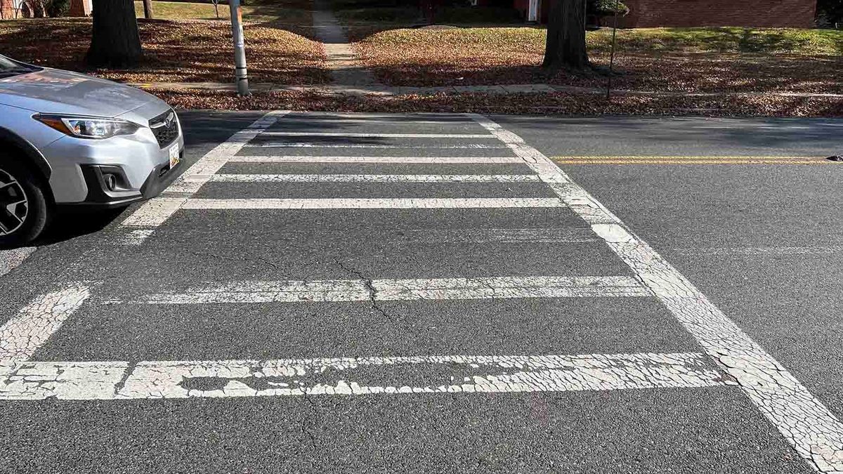 A crosswalk with a car just on the edge of entering it