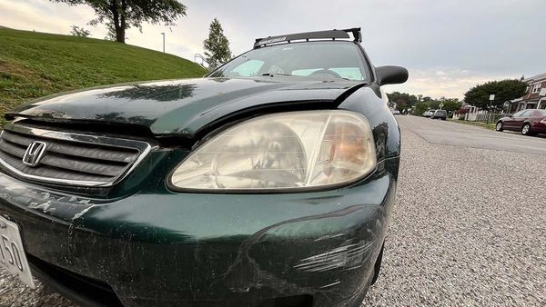 Closeup of driver's side front showing hood gap and scuffed bumper