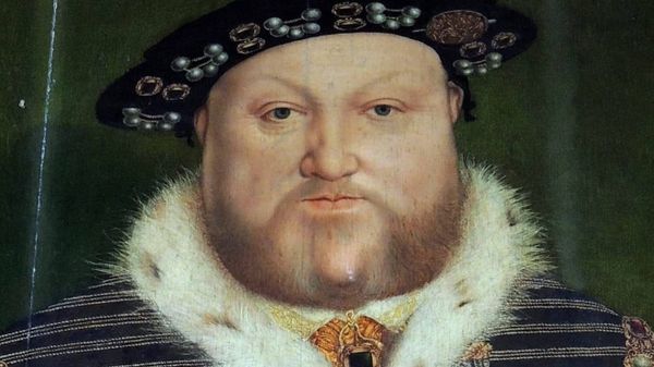 Henry in heavily bejeweled royal robe trimmed with fur, hand upon a royal staff. Dude does not look like fun.