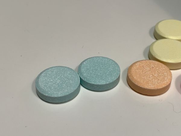 WEIRDLY GREENISH-BLUE CHALKY ANTACID TABLETS NEXT TO ORANGE AND YELLOW ONES