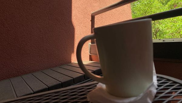 Mug of tea on a napkin on an outdoor table on a deck with a view of some trees
