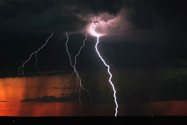 Multiple bolts of lightning against a dark sky and some of the bolts appear to be emanating from what looks like the moon behind roiling clouds but might be A HIGHER BEING