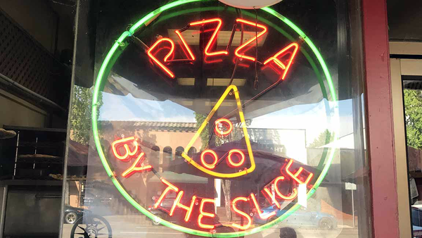 Neon window sign: PIZZA BY THE SLICE with a nice neon slice in there.