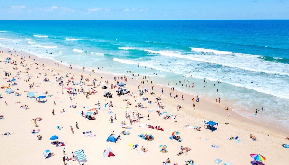 aerial view of many people on a beach, lots of umbrellas and towels