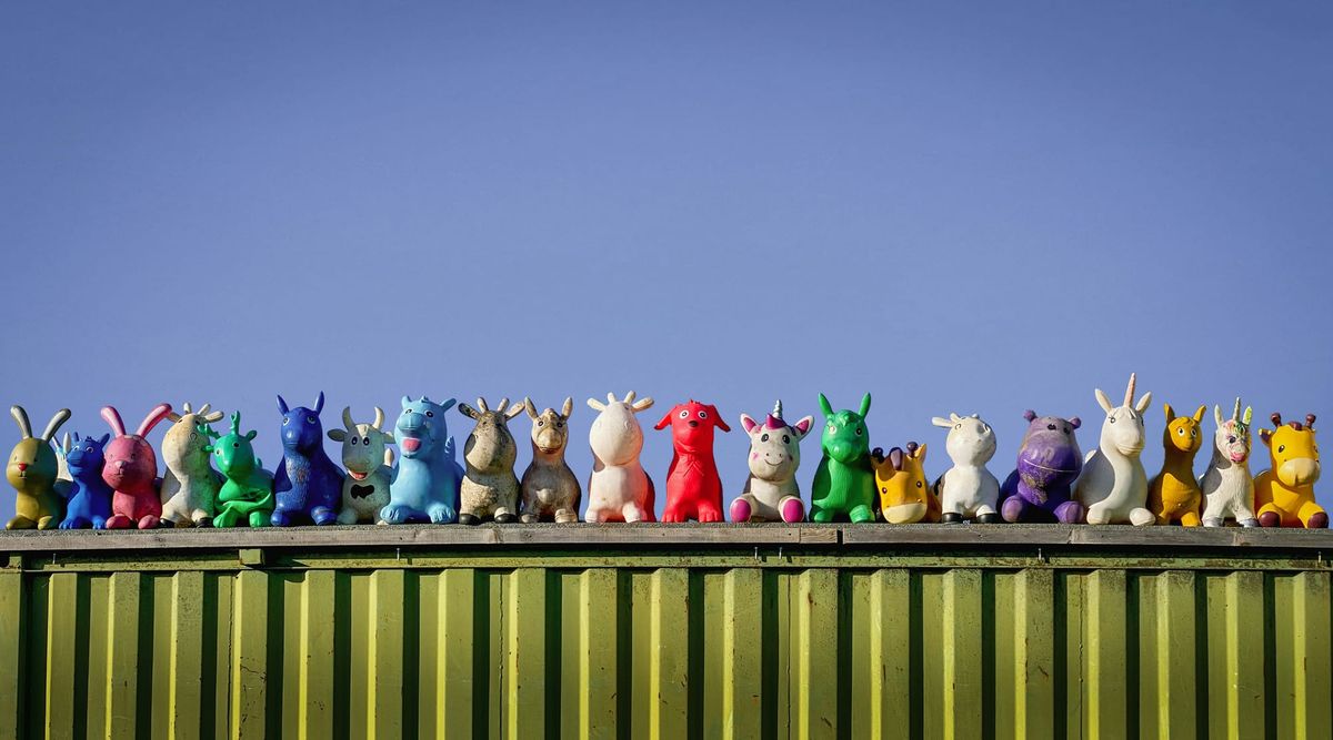 A line of colorful toy animals along a bright green wall with a blue sky in the background