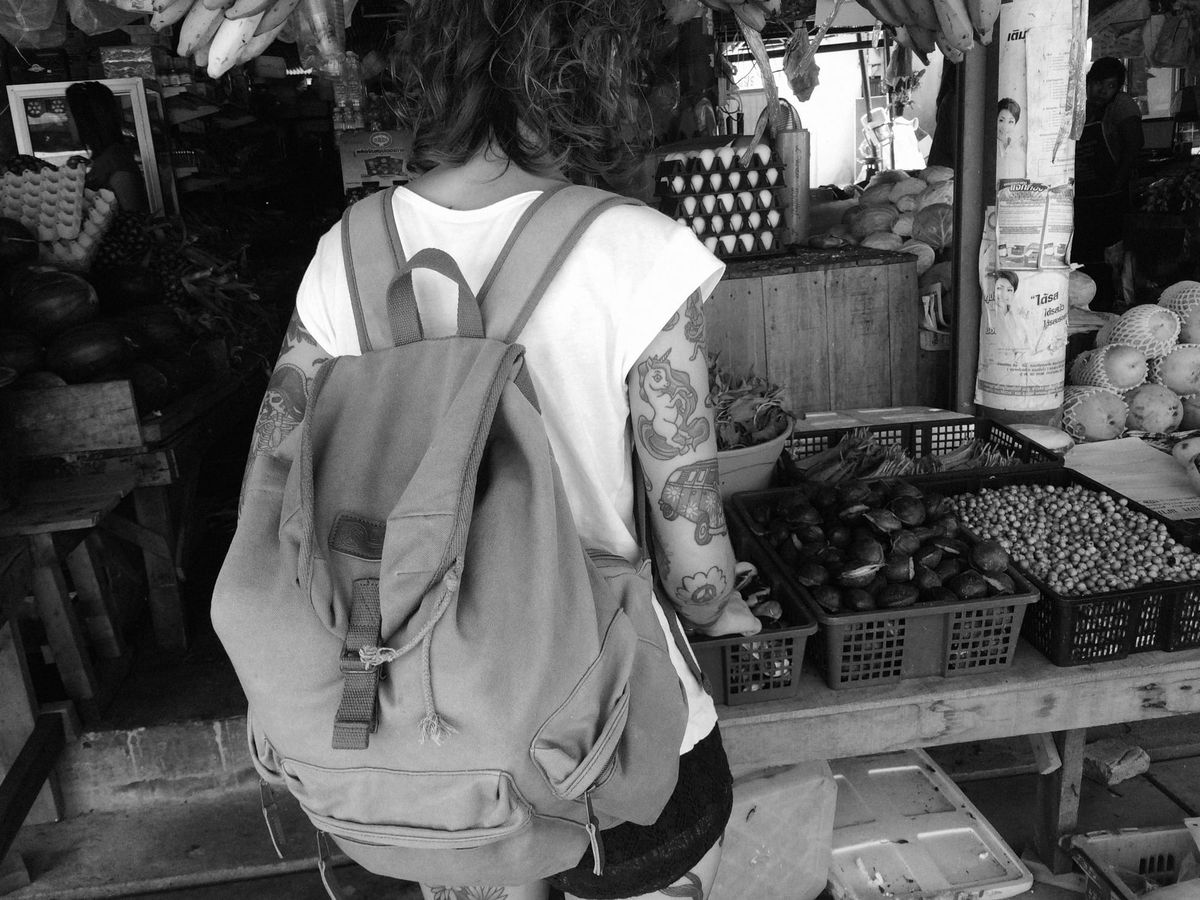Photo of a child wearing a backpack standing by food baskets at a store.