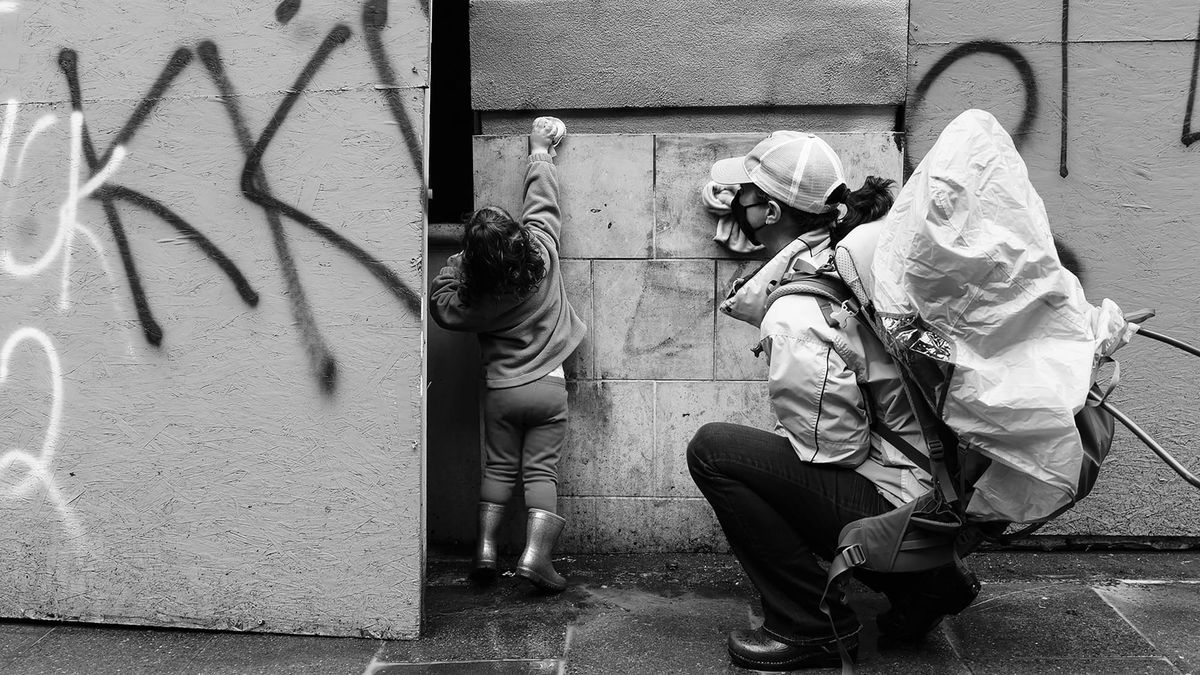 Photo of a child and an adult scrubbing graffiti off a wall together