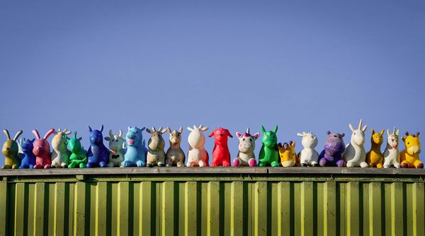 A line of colorful toy animals along a bright green wall with a blue sky in the background