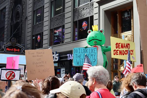 Inflatable frog wearing a crown with protestors in the foreground at October 2025 No Kings Protest in NYC