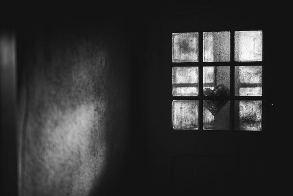 Black and white photo of a paned window with a heart in a darkened room