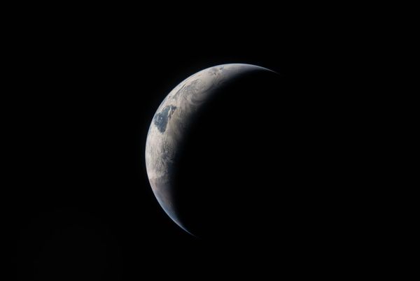 A NASA photo of Earth in shadow, taken from Artemis II. Only a crescent of Earth is visible amidst darknes.