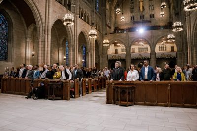 Congregation standing in the pews of The Riverside Church during the April 4, 2026 gathering, Gothic arches and "Christ Is Risen" banners visible in the background.