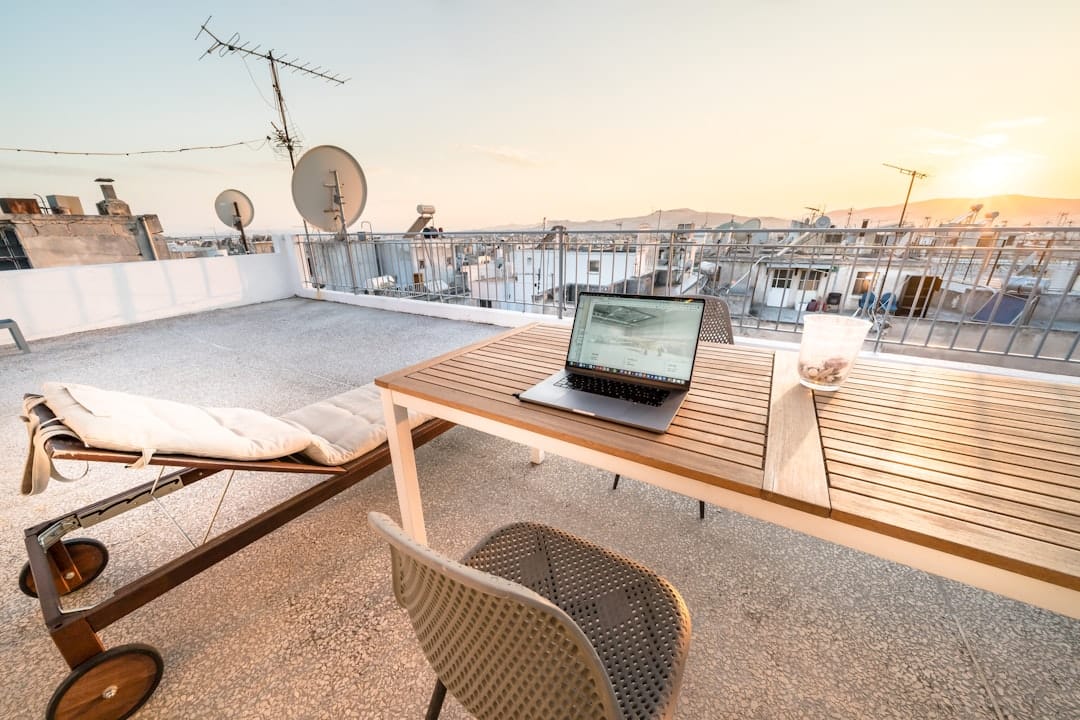 Laptop on table at rooftop with city view at sunset