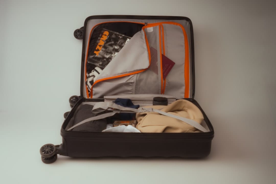 An open black suitcase packed with clothes and travel essentials.