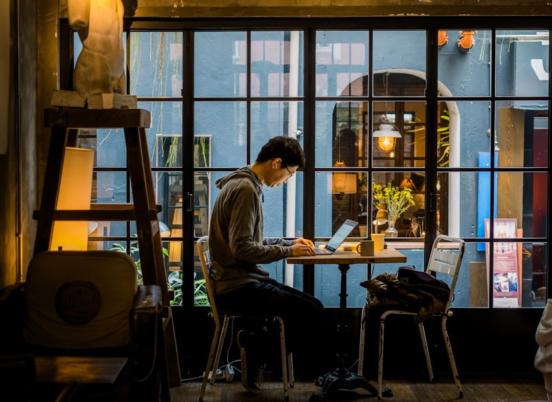 Man working on laptop in a cafe by the window.