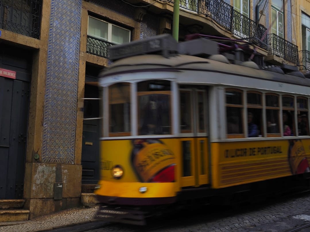 a yellow trolley car traveling down a street next to a tall building