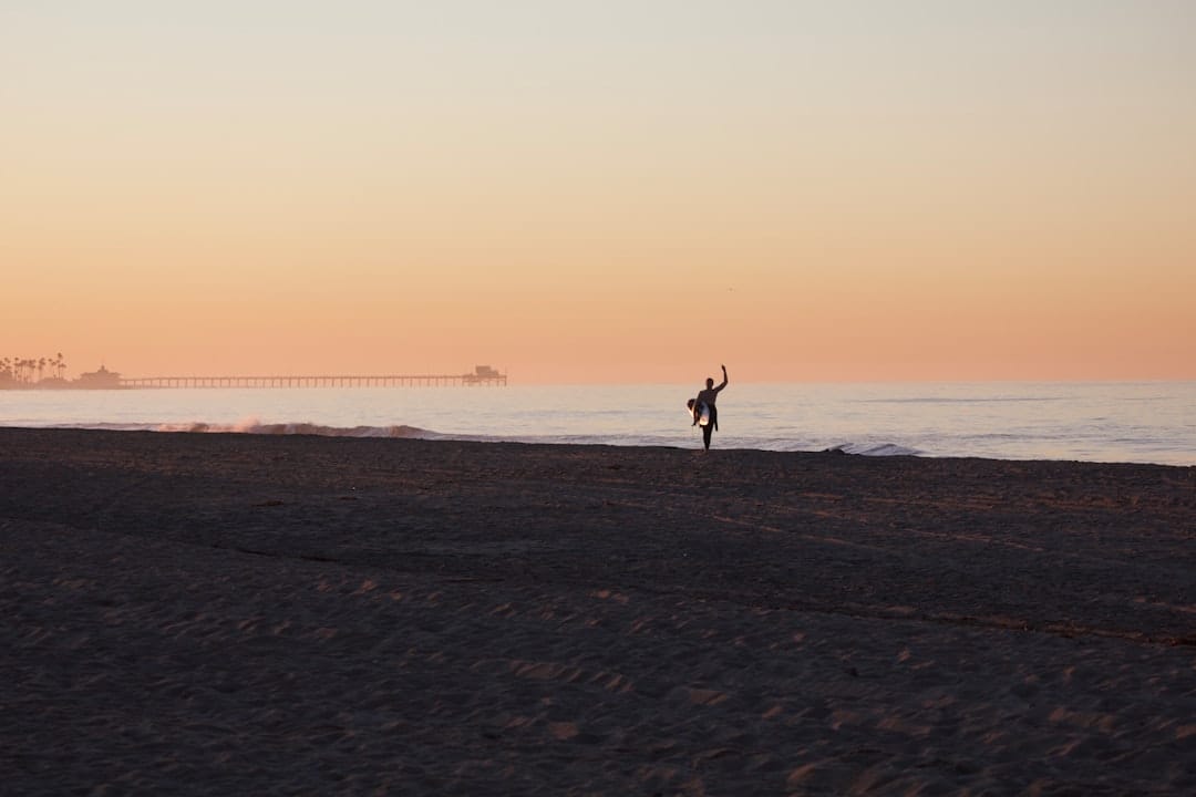 silhouette of person walking on beach during sunset