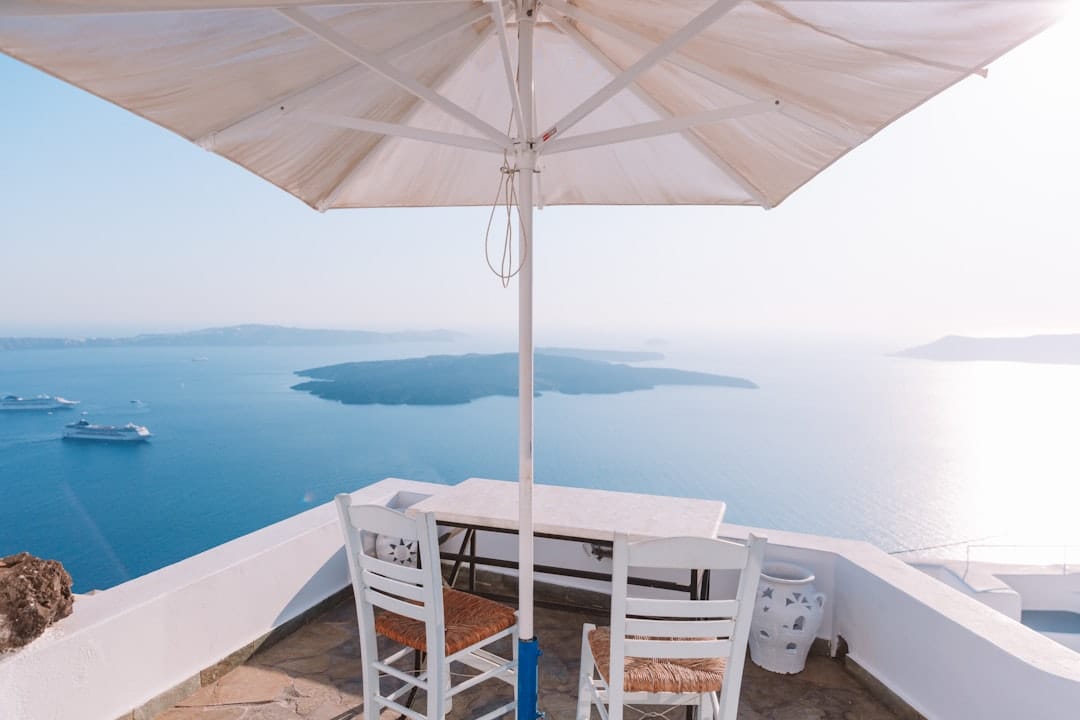 An umbrella shades a table overlooking the sea.