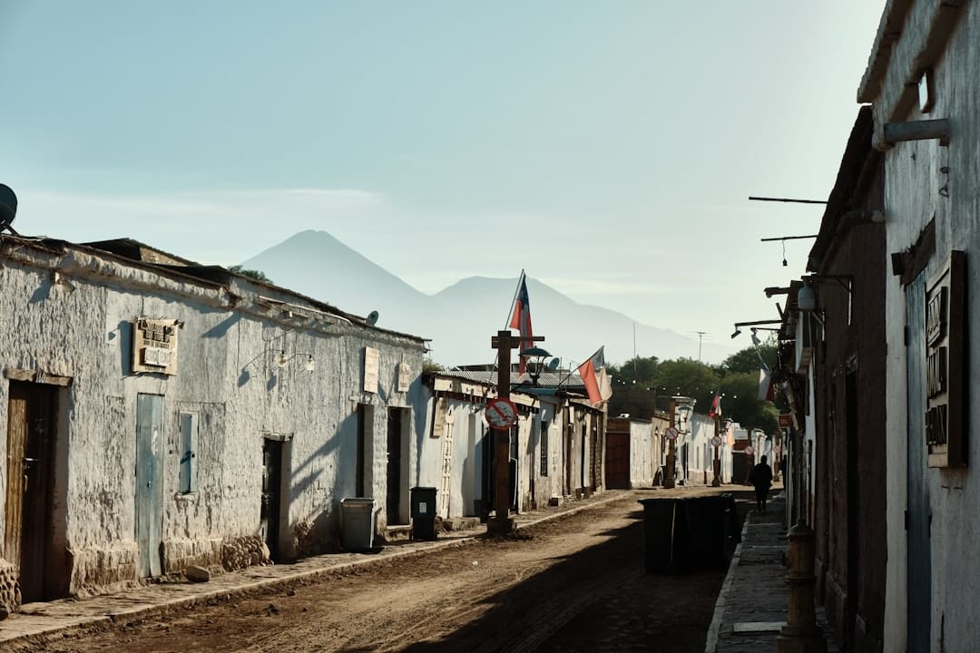 A dusty street in a small town with mountains beyond.