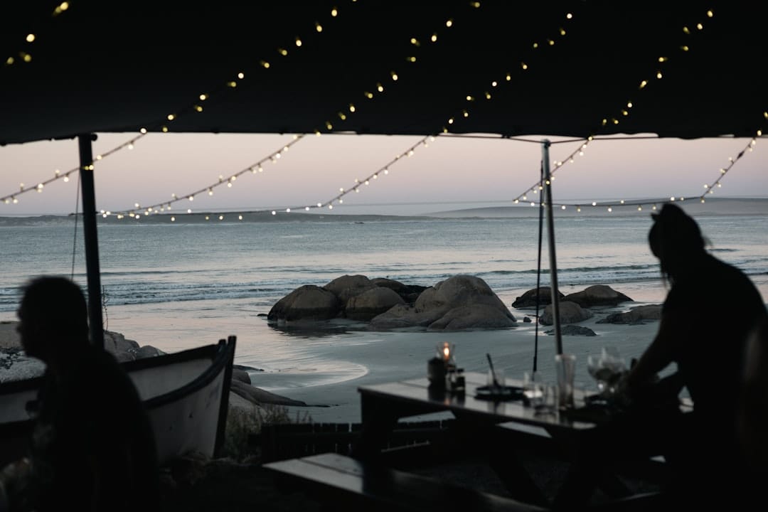 A couple of people sitting at a table near the ocean