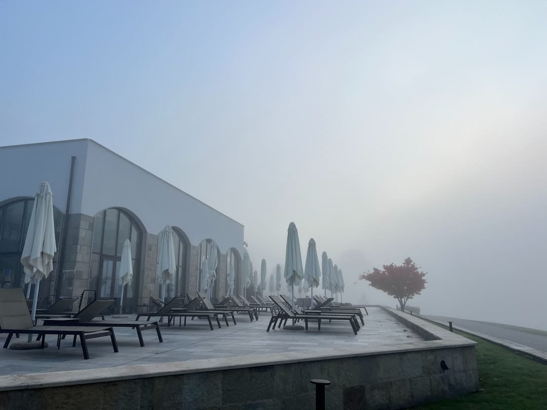 Lounge chairs on a foggy patio next to a building.