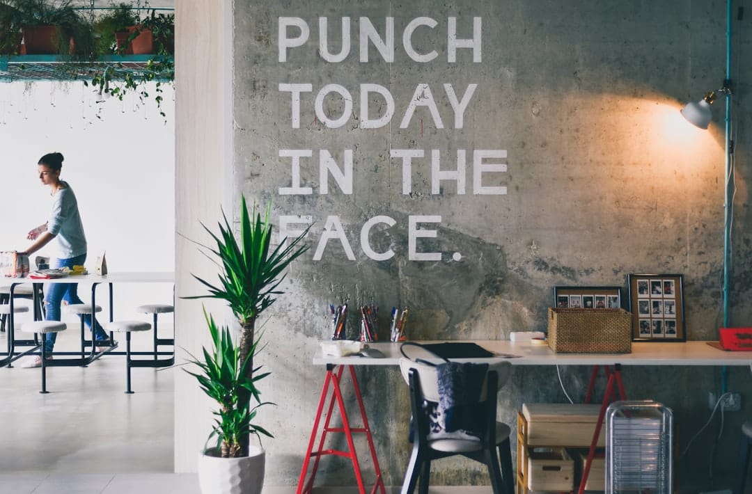 A person standing at a table in a workspace with a concrete wall