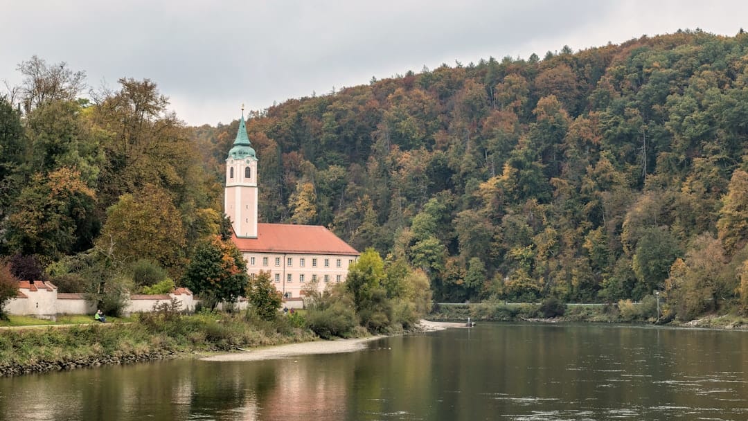 A building with a tower next to a calm river