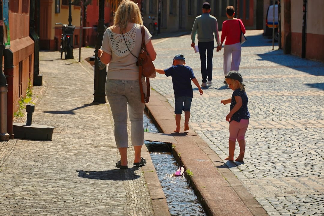 Family walks down a cobblestone street with a canal.