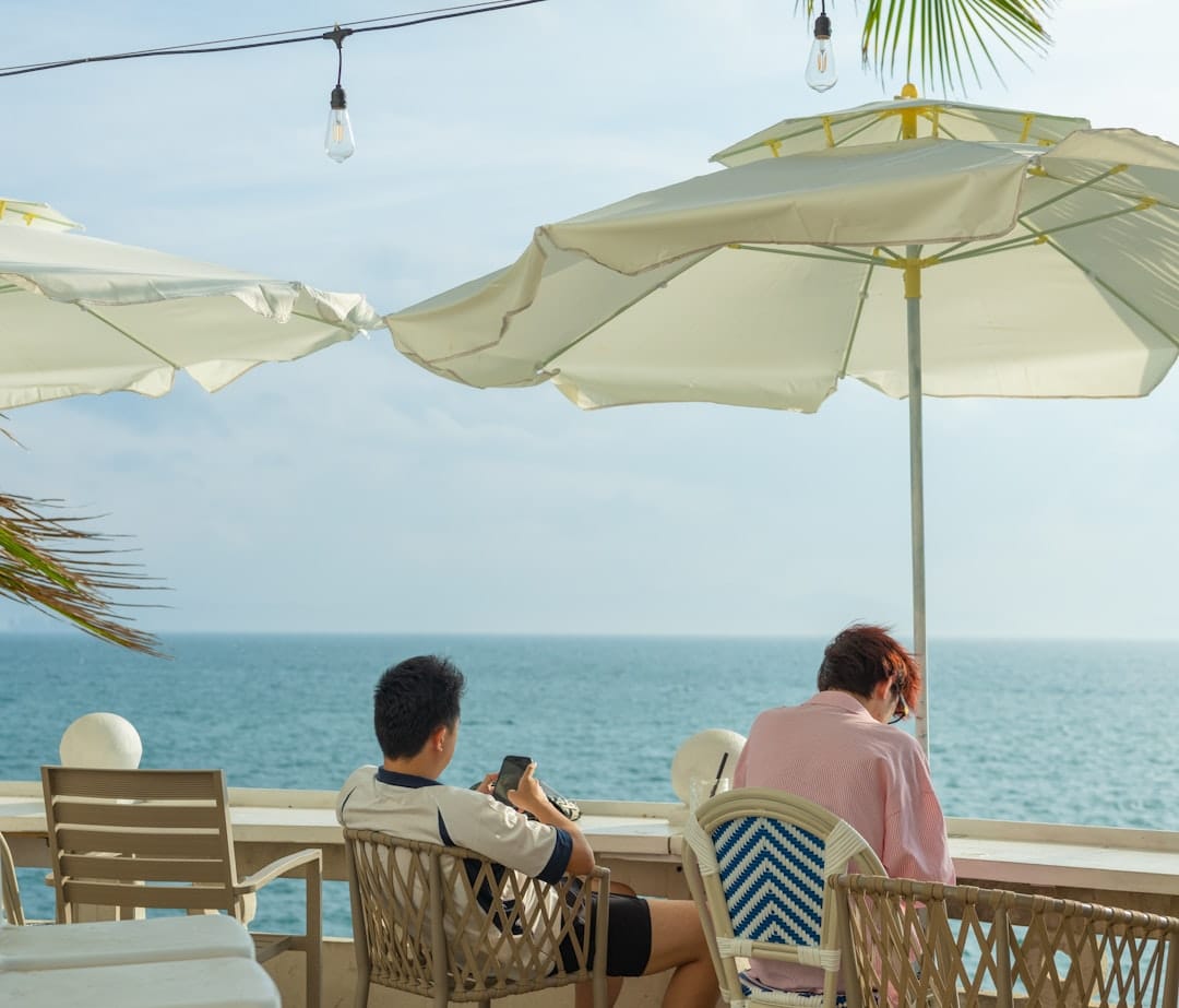 Two people relax at an outdoor cafe overlooking the ocean.