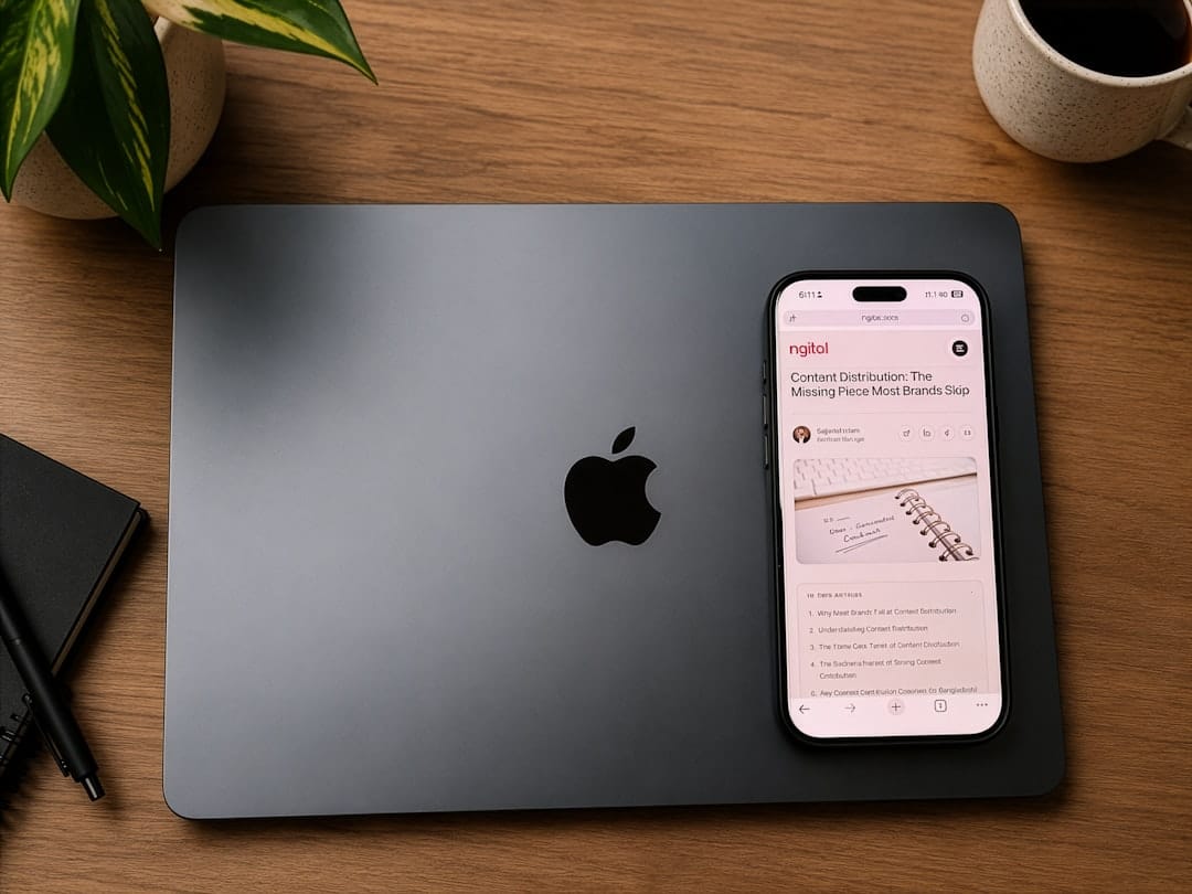 Apple laptop, smartphone, and coffee mug on a wooden desk.