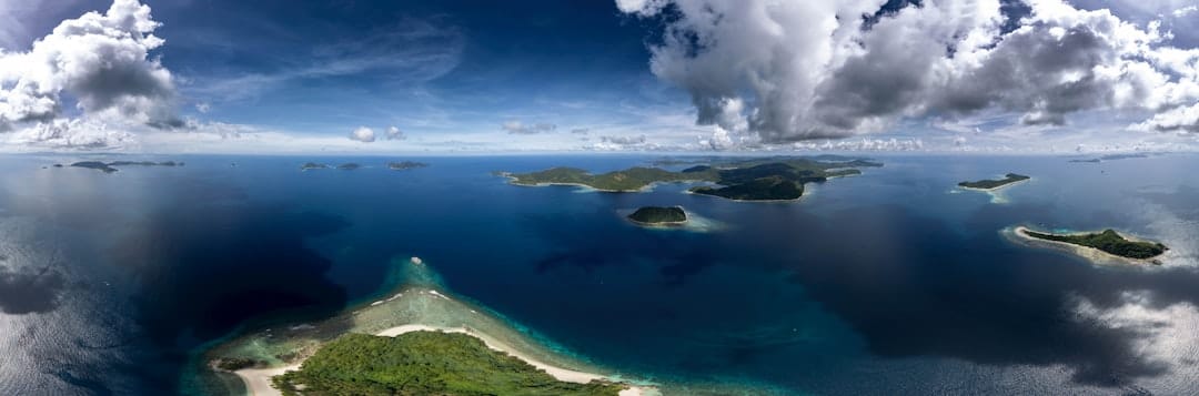 Islands scattered across a vast blue ocean under clouds.