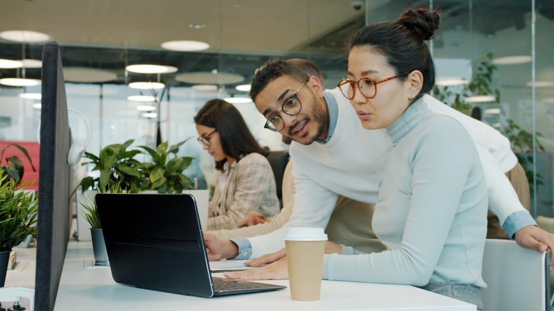 Two colleagues collaborating on a laptop in office