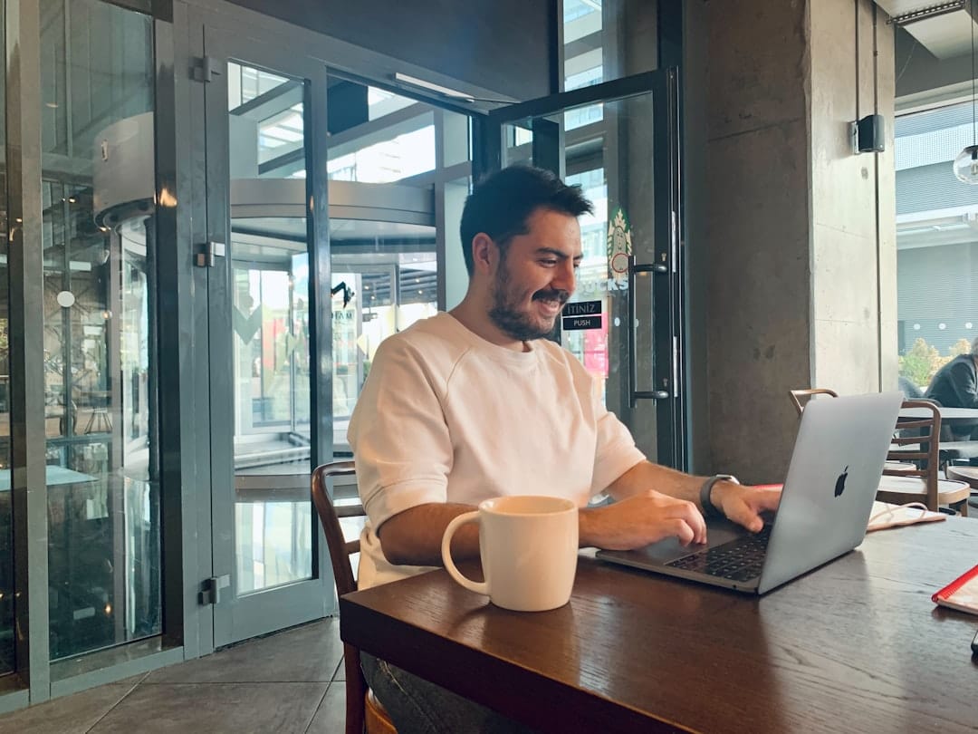 Man smiling while working on laptop in cafe