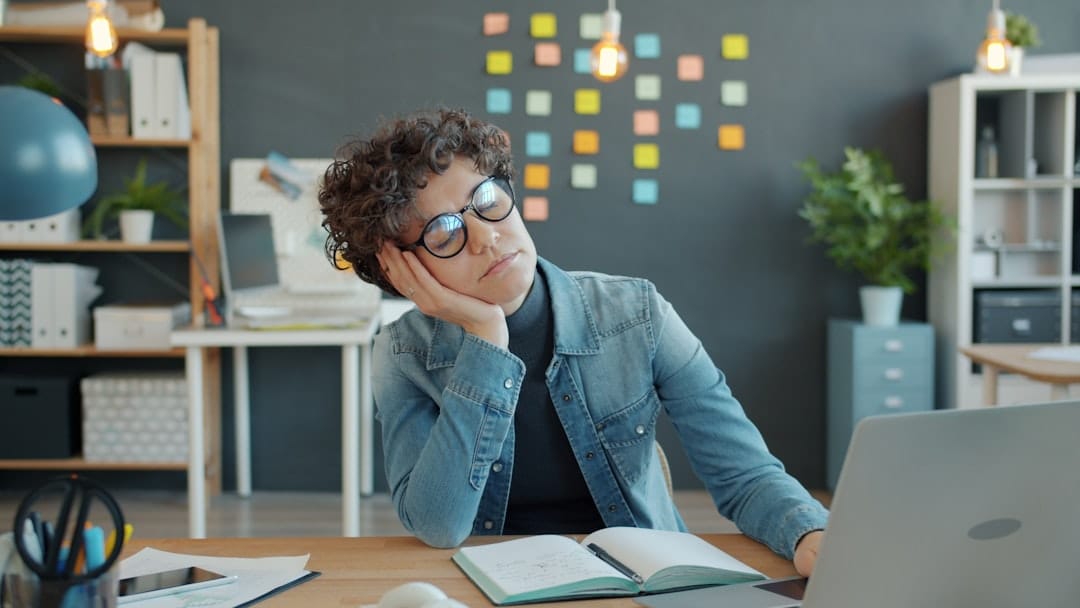 Tired person resting head on hand at desk