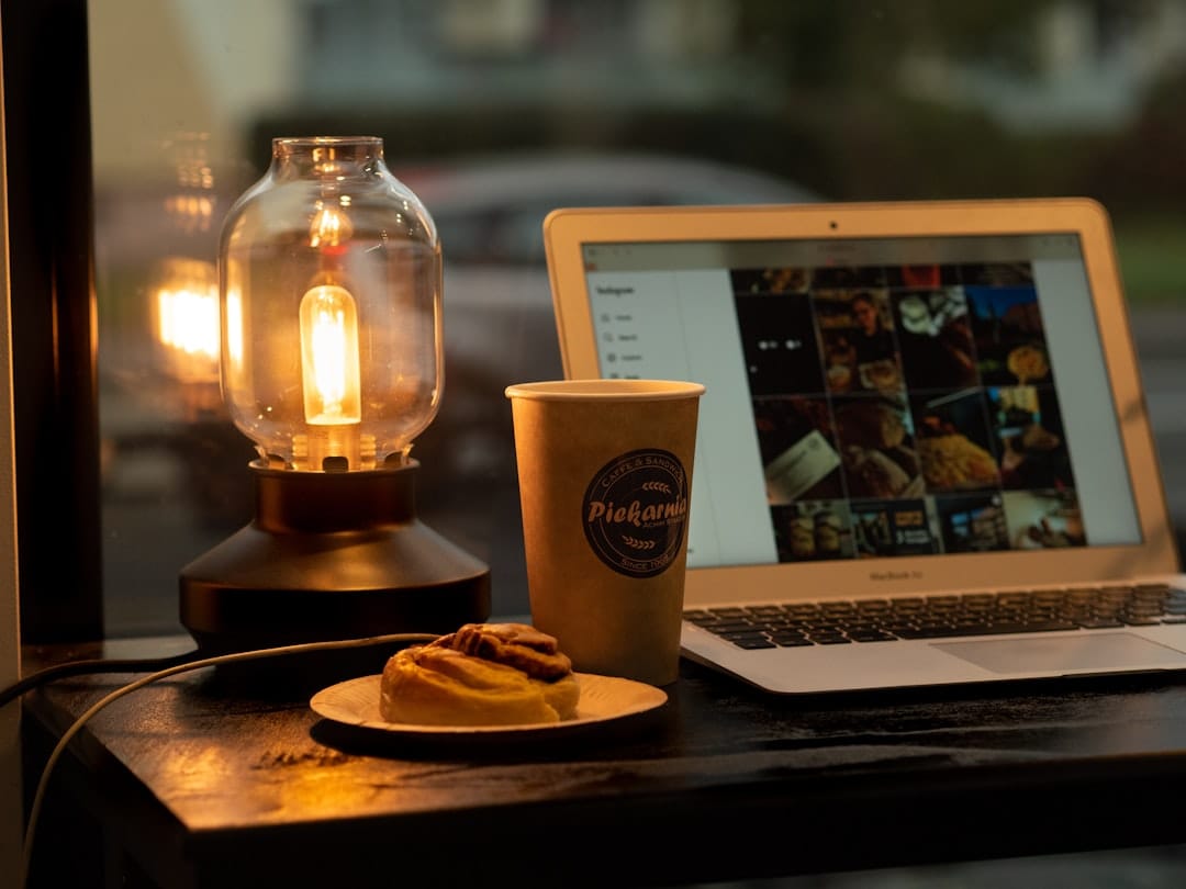 Laptop, coffee, and pastry by a vintage lamp