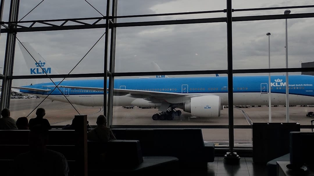 Blue klm airplane parked at an airport gate