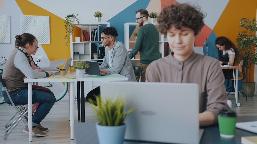 People working on laptops at desks in a colorful modern office workspace