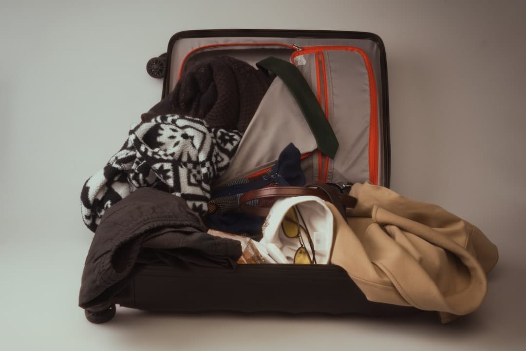 An open suitcase overflowing with various clothes