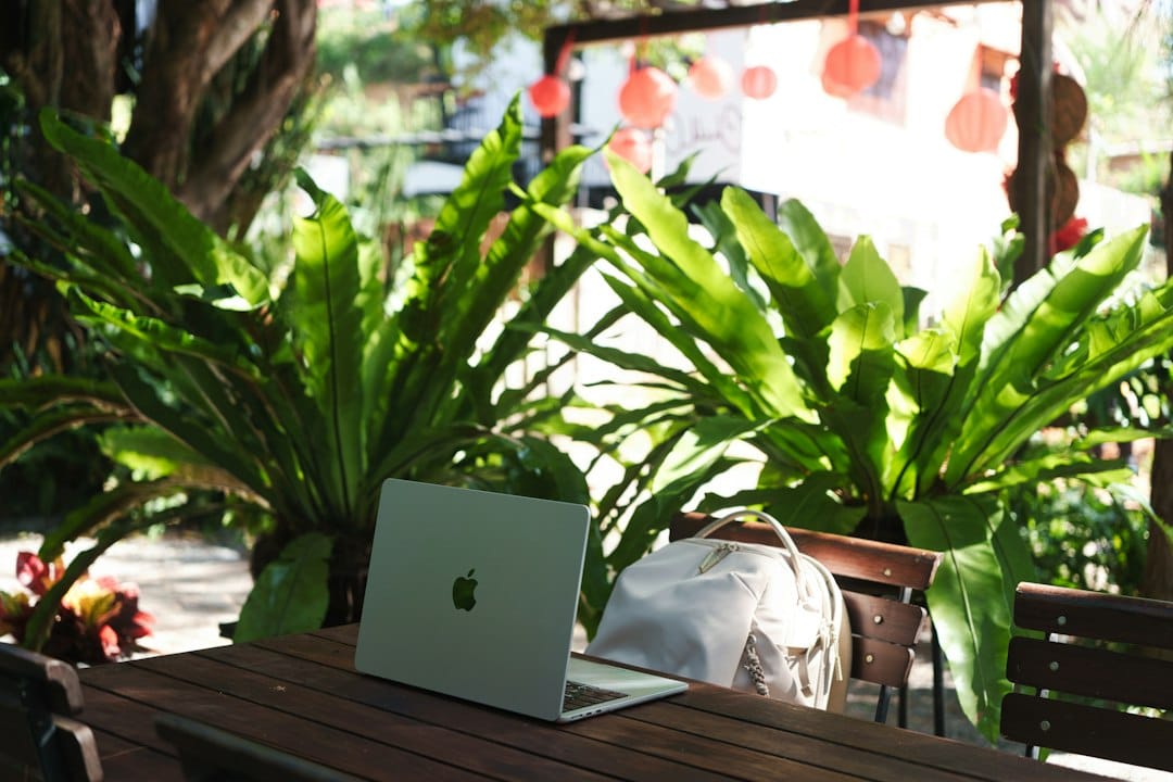 Laptop and backpack on a wooden table surrounded by plants