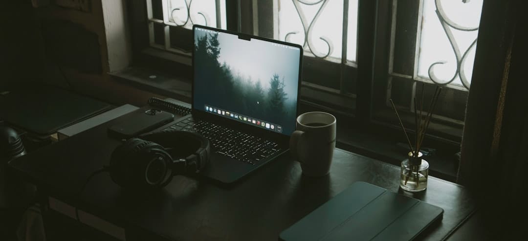 Desk with laptop, headphones, and coffee cup near window