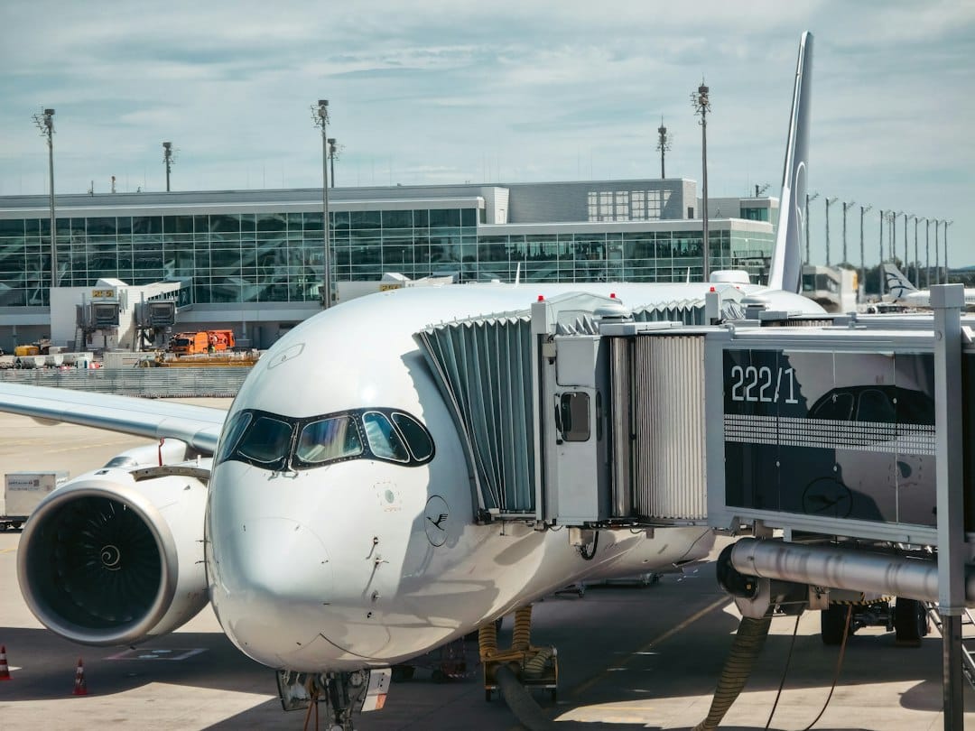 A white passenger airplane connected to a jet bridge at an airport terminal