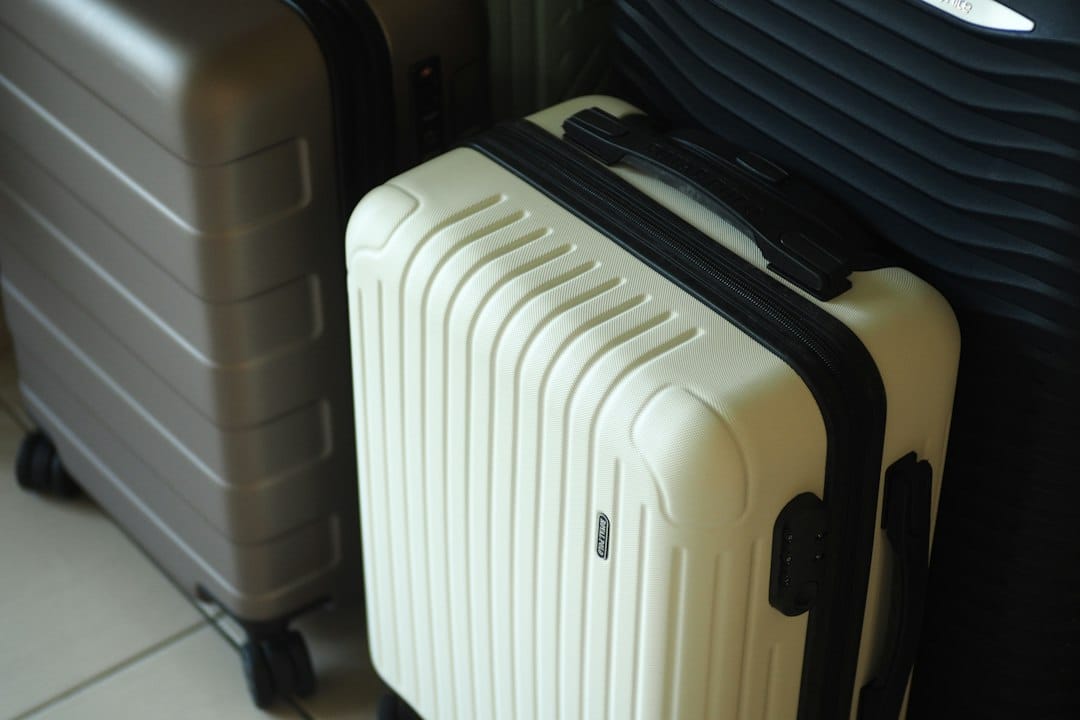 Three hard-shell suitcases in white, grey, and dark colors
