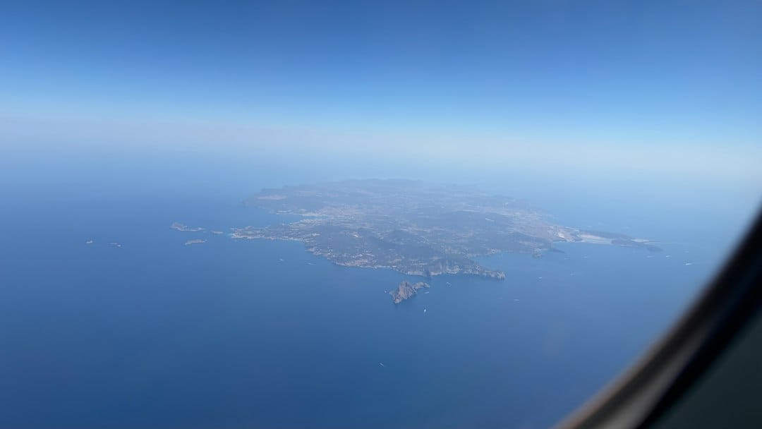 Island in blue ocean from an airplane window