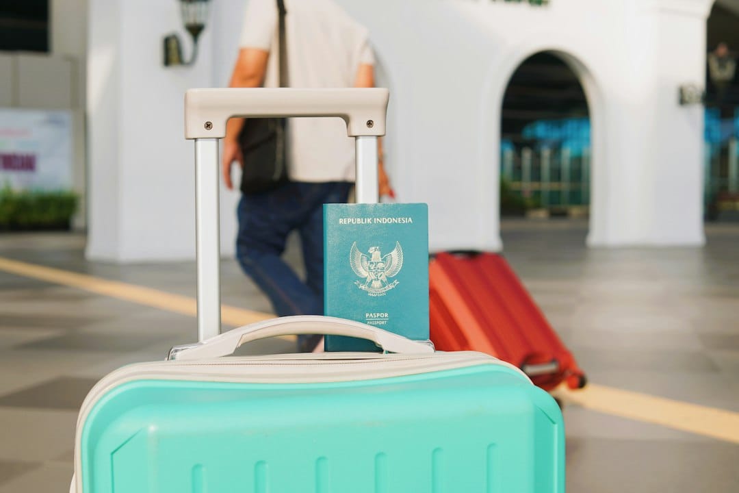 An Indonesian passport resting on a teal suitcase handle at an airport terminal