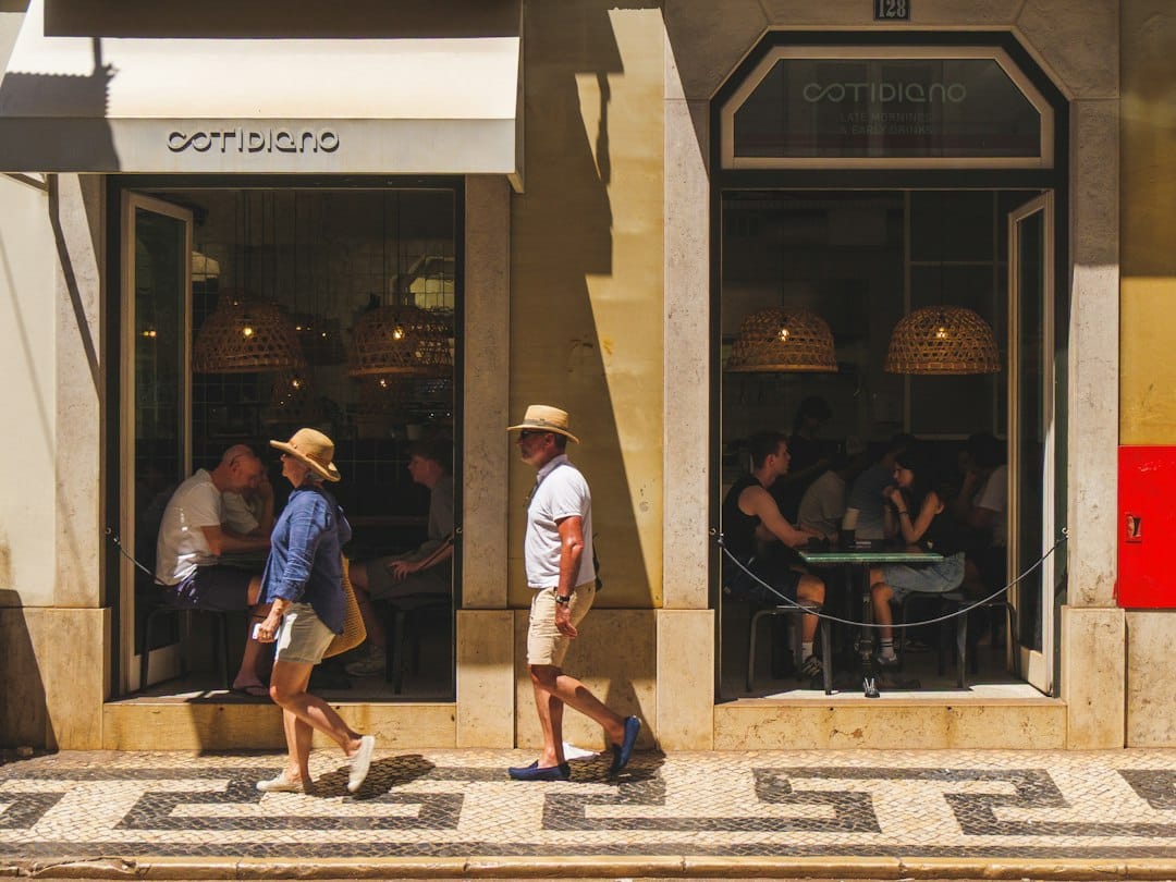 People walk past a cafe on a sunny day