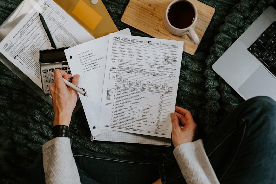 Person reviewing documents with calculator and laptop