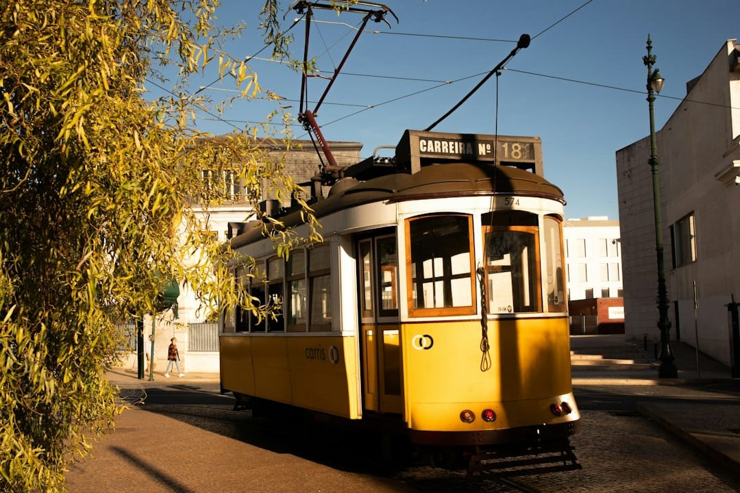 A classic yellow tram travels down a sunny street
