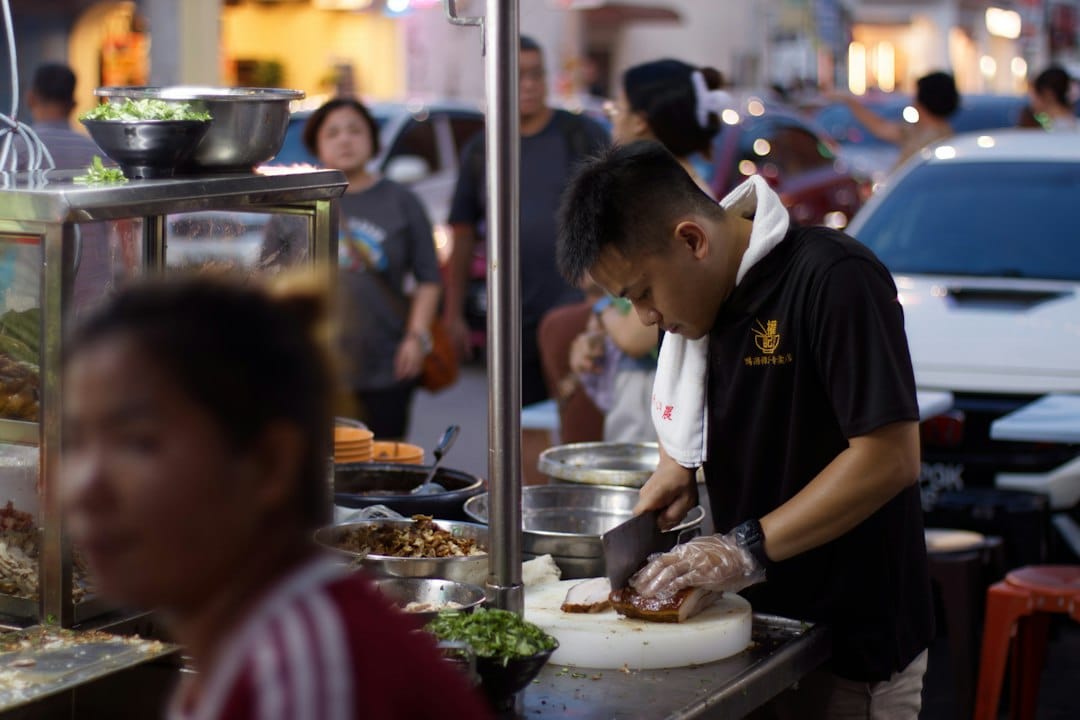 A vendor prepares food at a busy street stall