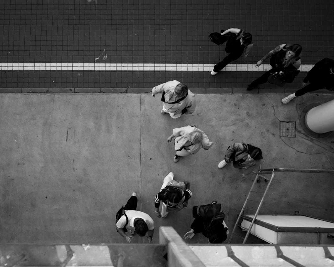A high-angle view of people walking on a concrete sidewalk near a tiled path