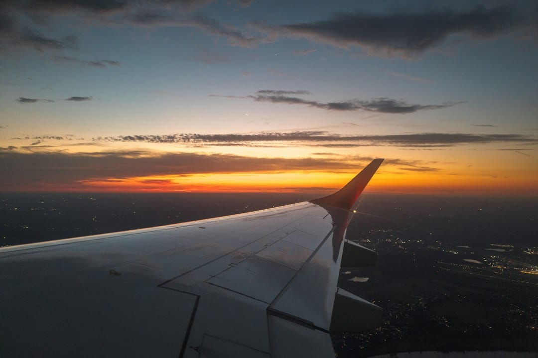Airplane wing against a sunset sky over city lights